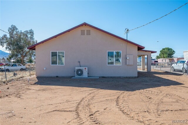 view of side of home featuring ac unit, fence, and stucco siding