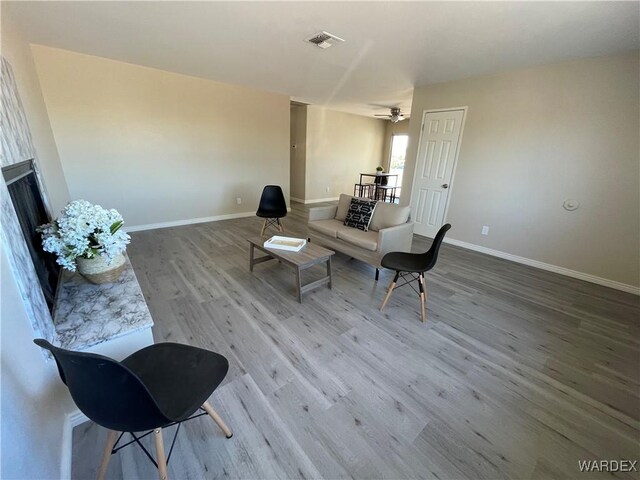 living area with a ceiling fan, baseboards, visible vents, and wood finished floors