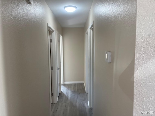 hallway featuring baseboards and wood finished floors