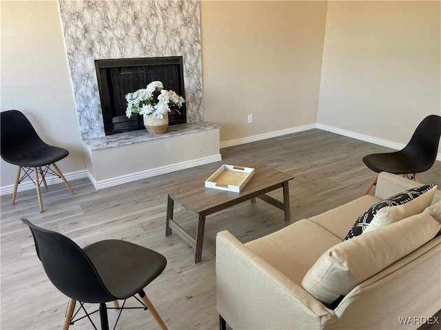 living area with a fireplace, wood finished floors, and baseboards