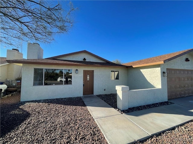 ranch-style home with a chimney, an attached garage, and stucco siding