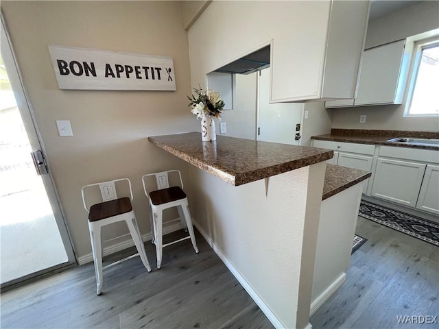 1720 E Valencia Rd, Fort Mohave, AZ 86426 - kitchen featuring dark countertops, light wood-style floors, and a kitchen breakfast bar