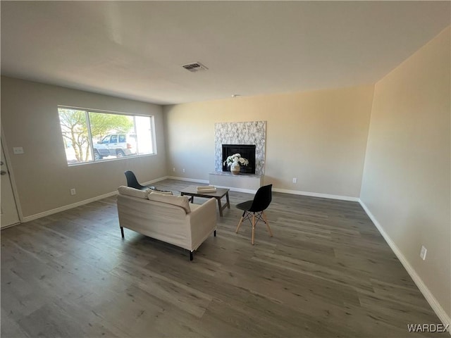 living room featuring dark wood-style floors, baseboards, a fireplace, and visible vents