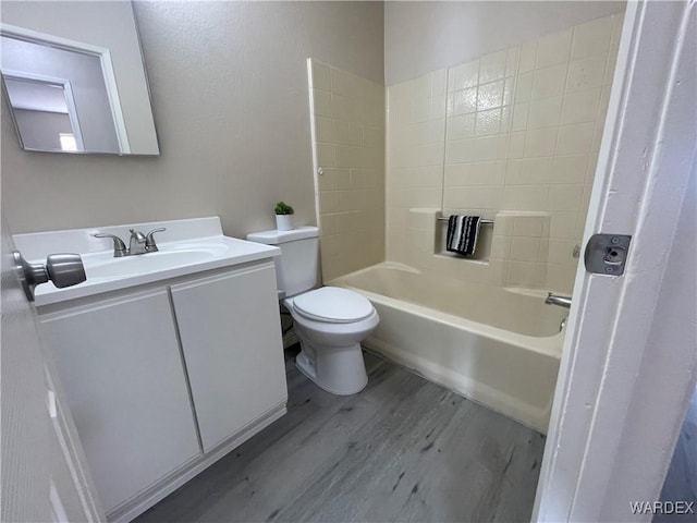 full bathroom featuring toilet, washtub / shower combination, wood finished floors, and vanity