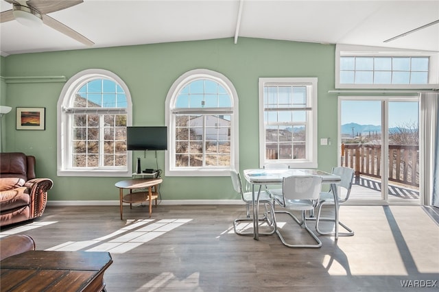 interior space with ceiling fan, baseboards, wood finished floors, and vaulted ceiling with beams