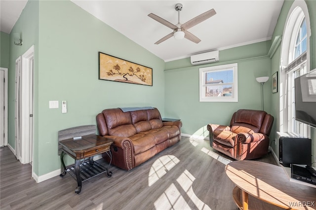 living area with baseboards, lofted ceiling, a wall unit AC, wood finished floors, and a ceiling fan