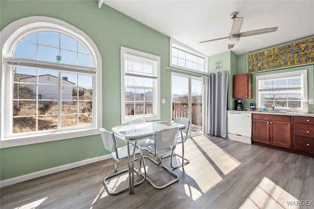 dining space with baseboards, plenty of natural light, lofted ceiling, and light wood-style flooring