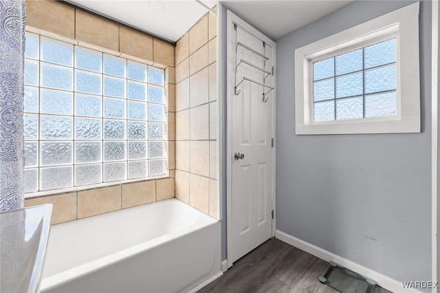 bathroom with walk in shower, baseboards, a tub to relax in, and wood finished floors