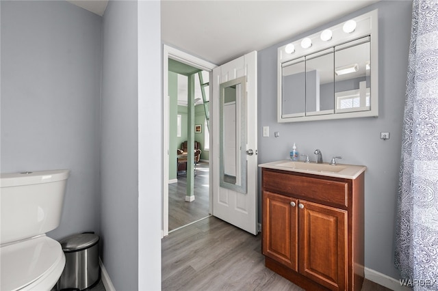 full bathroom featuring toilet, vanity, baseboards, and wood finished floors