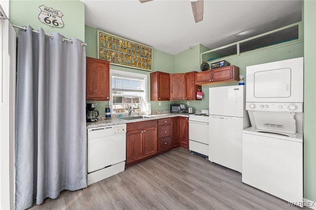 kitchen with light wood-style flooring, a sink, white appliances, stacked washer / dryer, and ceiling fan