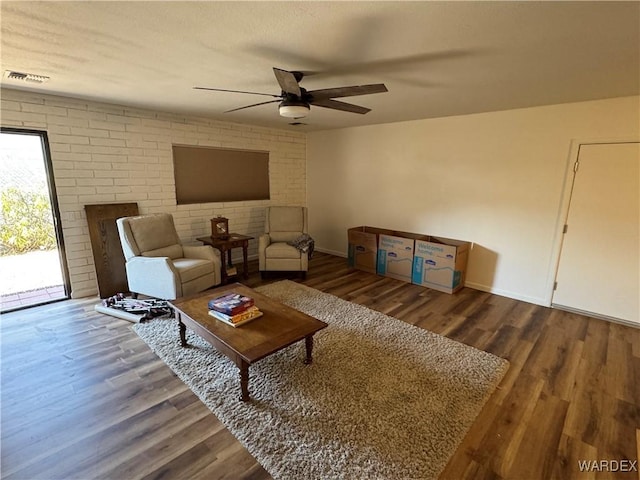 living area featuring baseboards, wood finished floors, visible vents, and a ceiling fan