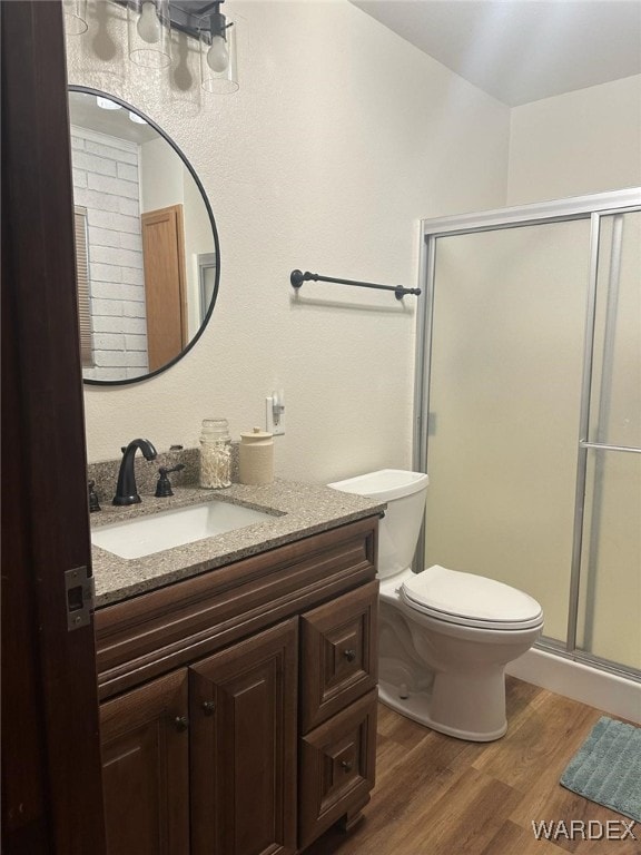 bathroom with a stall shower, vanity, toilet, and wood finished floors