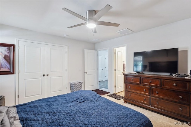 bedroom with attic access, visible vents, light colored carpet, ceiling fan, and a closet