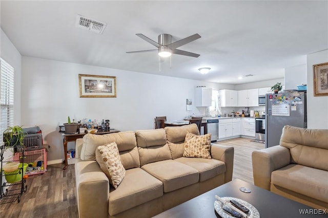 living room featuring plenty of natural light, wood finished floors, visible vents, and a ceiling fan