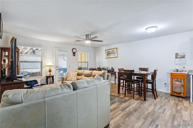 living room with ceiling fan, baseboards, and wood finished floors