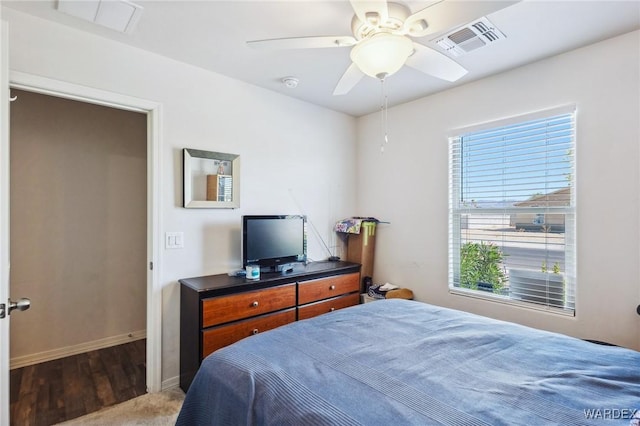 bedroom featuring visible vents, ceiling fan, baseboards, and wood finished floors