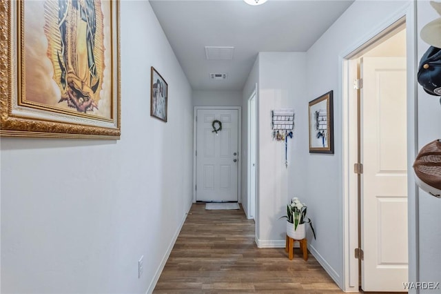 hall with dark wood-type flooring, visible vents, and baseboards