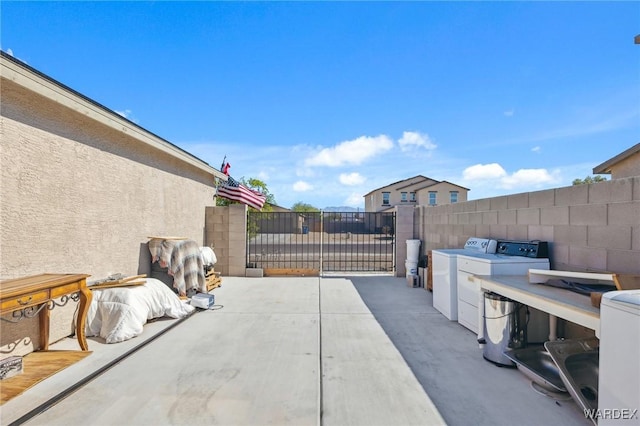 view of patio / terrace with washing machine and dryer, a gate, and fence