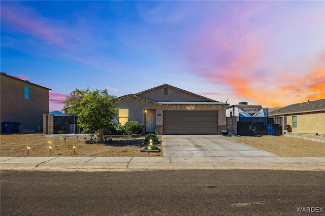 ranch-style home with driveway, an attached garage, fence, and stucco siding