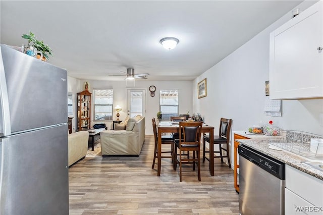 kitchen with light wood finished floors, appliances with stainless steel finishes, white cabinets, and open floor plan