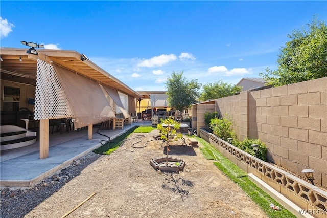 view of yard featuring a garden, a fenced backyard, and a patio