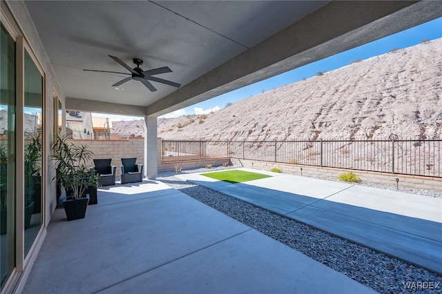 view of patio with ceiling fan, a fenced backyard, and a mountain view