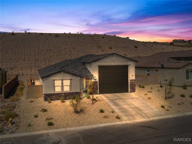 view of front of property featuring a garage, stone siding, driveway, and stucco siding