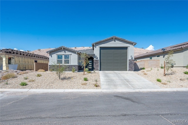 view of front facade with a garage, fence, stone siding, concrete driveway, and stucco siding