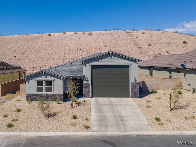 view of front facade with a garage, stone siding, driveway, and stucco siding