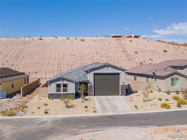 view of front facade featuring a garage, stone siding, driveway, and stucco siding