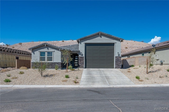 view of front of property featuring driveway, stone siding, a garage, and stucco siding