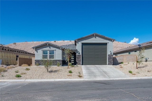 view of front facade with an attached garage, fence, driveway, stone siding, and stucco siding