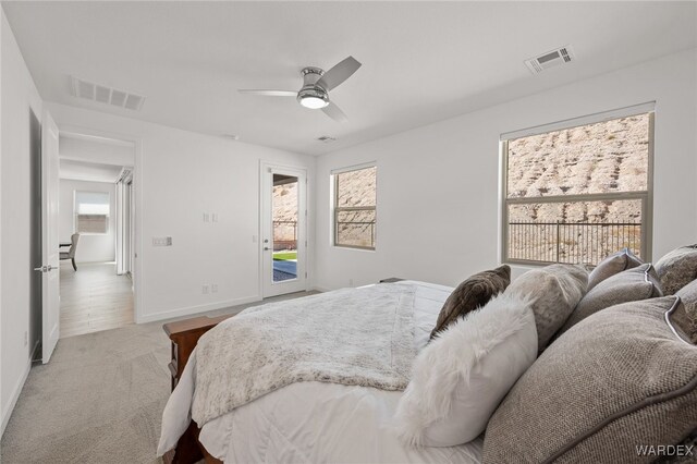 bedroom with access to outside, visible vents, ceiling fan, and light carpet