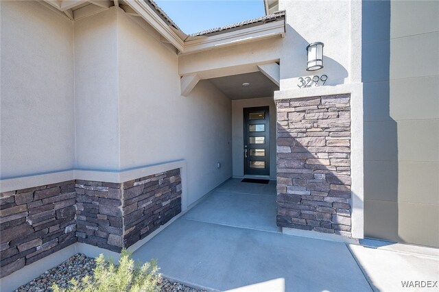 view of exterior entry featuring stone siding and stucco siding