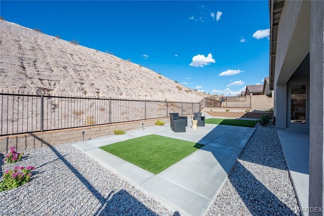 view of yard with a fenced backyard, a mountain view, and a patio