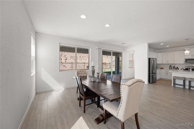 dining room with recessed lighting, baseboards, and light wood finished floors