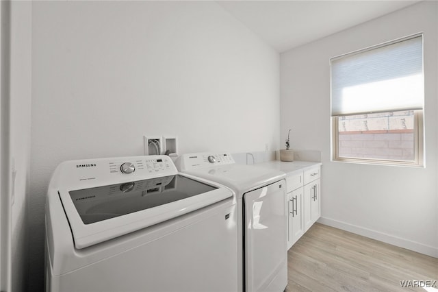 washroom featuring cabinet space, independent washer and dryer, light wood-style flooring, and baseboards