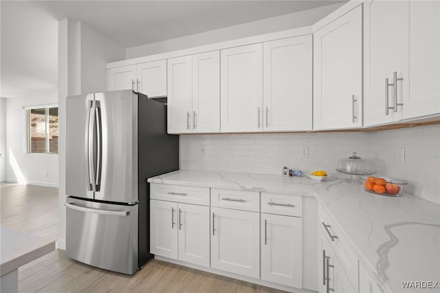 kitchen featuring light stone countertops, white cabinetry, and freestanding refrigerator