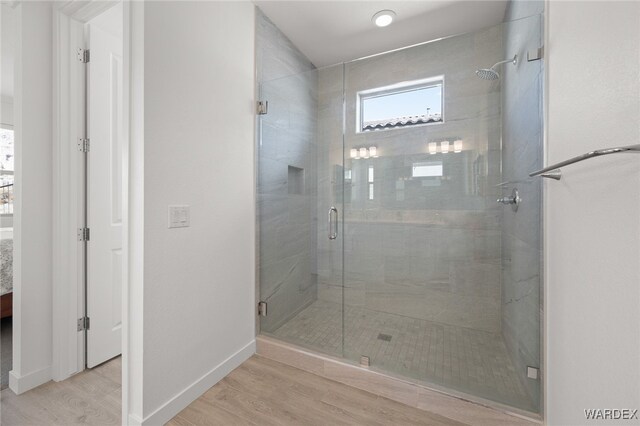 ensuite bathroom featuring ensuite bathroom, a shower stall, baseboards, and wood finished floors