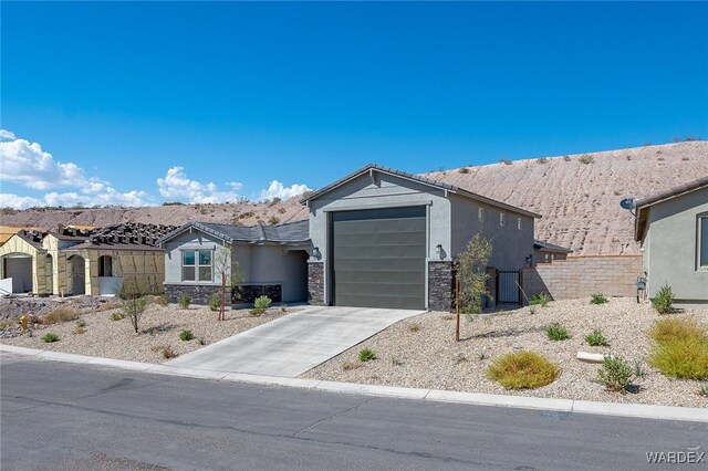 view of front of property with a garage, stone siding, driveway, and stucco siding