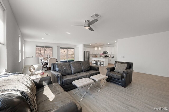 living room featuring light wood-type flooring, baseboards, visible vents, and recessed lighting