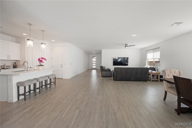 living area featuring light wood-type flooring, ceiling fan, visible vents, and a toaster