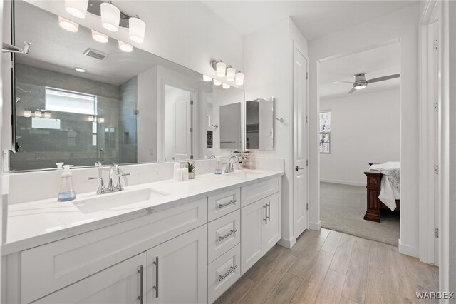 full bathroom featuring double vanity, a shower stall, a sink, and ensuite bathroom