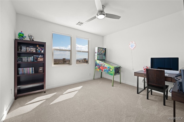 office space featuring baseboards, a ceiling fan, visible vents, and light colored carpet