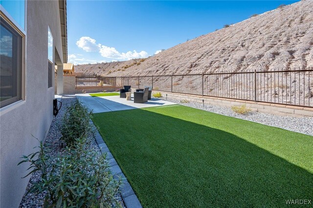 view of yard featuring a patio area, a fenced backyard, and a mountain view