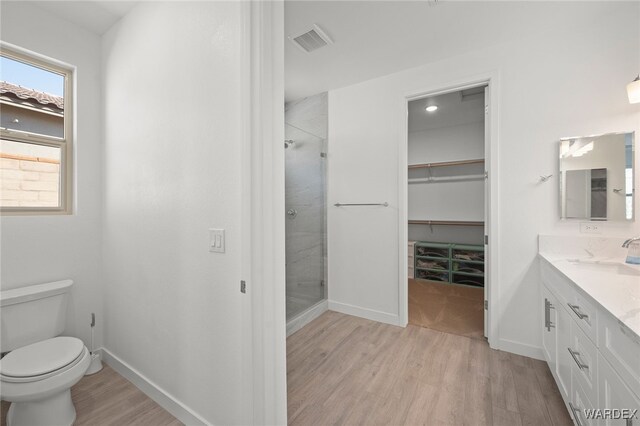 full bath with visible vents, a spacious closet, toilet, a stall shower, and wood finished floors