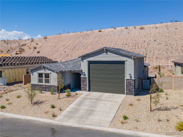 view of front facade with an attached garage, stone siding, driveway, and stucco siding