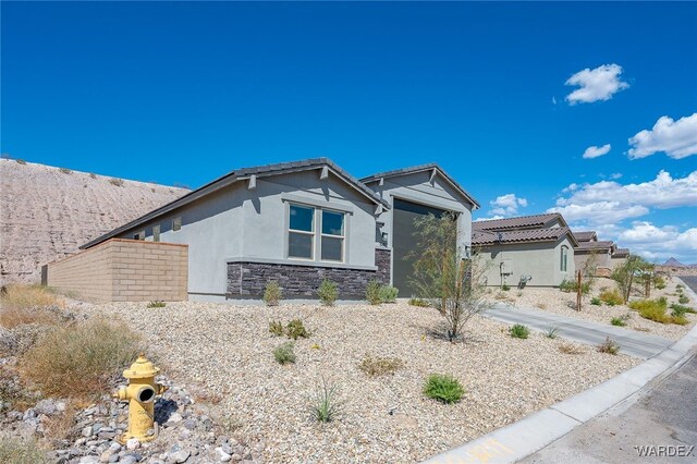 view of front of house featuring a garage, stone siding, driveway, and stucco siding