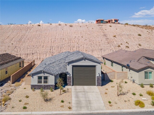 ranch-style home featuring an attached garage, stone siding, concrete driveway, and stucco siding