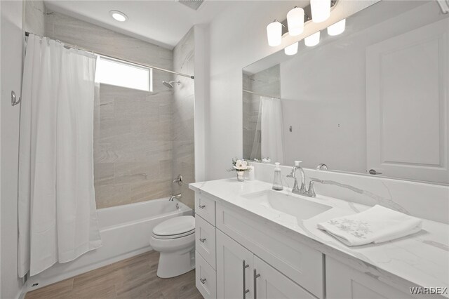 full bathroom featuring wood finished floors, vanity, toilet, and shower / bath combo with shower curtain